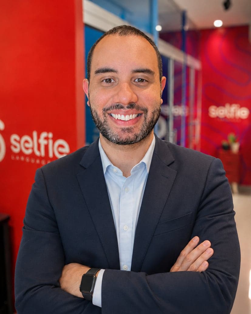 De blazer, no corredor da Selfie, com a parede da marca ao fundo.